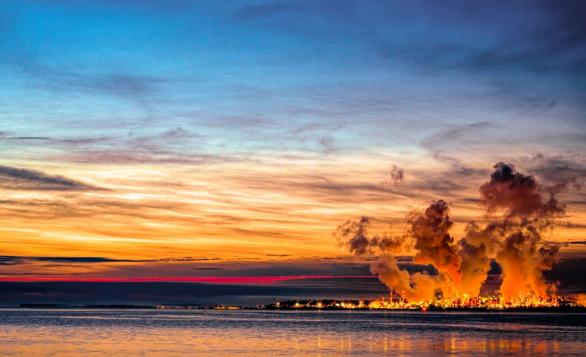Industrieanlage mit Treibhausgasemissionen bei Sonnenuntergang – Symbolbild für die Bilanzierung von Unternehmensemissionen nach GHG Protocol und ISO 14064.